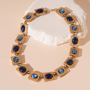Macro detail of vintage square gold necklace with deep blue and faceted light blue stones