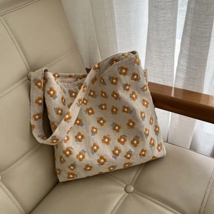 Detail of yellow flower embroidery and simple wish label on beige cotton canvas bag