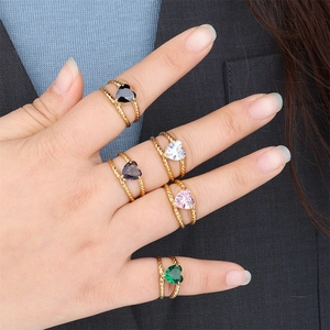 Close-up of heart-shaped zircon rings in five colors with gold braided texture bands