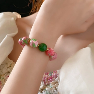 Detail of beaded ceramic bracelet with floral patterns and gold plating on model wrist
