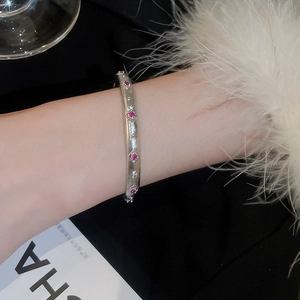 Detailaufnahme eines gebürsteten Silberarmbands mit roten Rubin-Edelsteinen