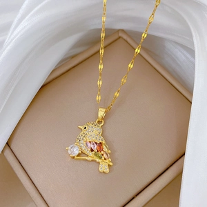 Golden bird necklace with colorful gemstones and pavé crystals on a silk background