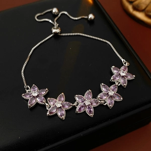 Detail eines verstellbaren Silberarmbands mit lila Zirkonia-Blütenanhängern auf schwarzem Leder