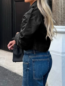Rückansicht einer schwarzen Satinjacke und blauen Jeans in einer städtischen Umgebung