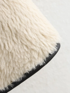 Detailansicht von Plüsch-Kunstpelz in Creme mit schwarzem Lederkontrast am Saum