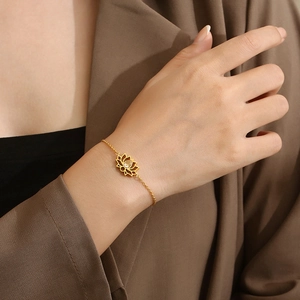 Close-up of golden stainless steel bracelet with hollow lotus charm and zircon gem