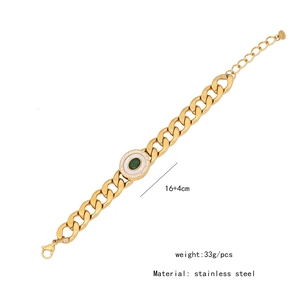 Macro detail of gold stainless steel Cuban chain bracelet with green gemstone pendant