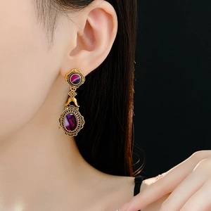 Close-up of vintage golden oval earrings with purple stones on a model