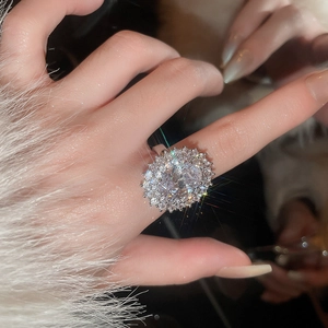 Close-up of a silver oval zircon ring with luxury crystal halo on a model hand