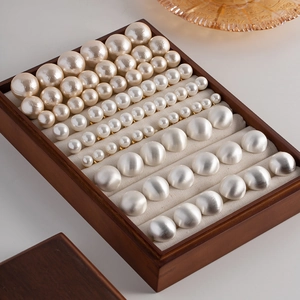 Detail showing assorted round cream pearls in a wooden jewelry display tray
