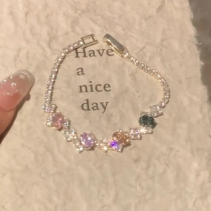 Elegant gold oval bracelet with colorful zircon stones on soft white texture
