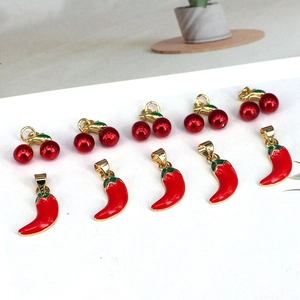 Detail view of red enamel cherry and chili charms with gold loops for DIY jewelry