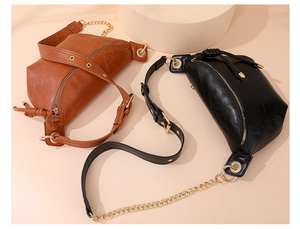 Makroaufnahme von braunen und schwarzen Ledertaschen mit Goldketten und Ösenverzierung