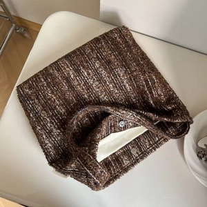 Detailed macro view of brown tweed shoulder bag texture with magnetic metal closure