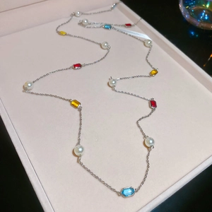 Detail view of long necklace with colorful octagon gemstones and white pearls in a gift box