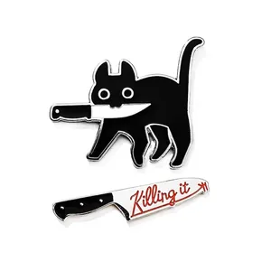 Detail of two-piece enamel pin set featuring a black cat with a knife and Killing it text