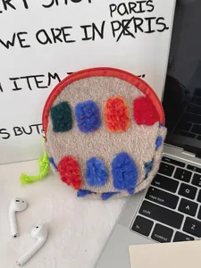 Round fleece storage bag with colorful felt patches and green lanyard on a desk
