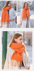 Close-up of orange cashmere-like scarf with tassels in an urban street style setting