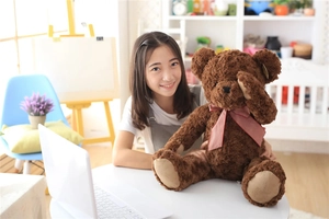 Detail of a brown teddy bear plush with a red checkered bow in a cozy home setting