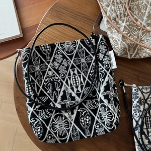 Close-up of vintage black canvas crossbody bag with white floral embroidery patterns