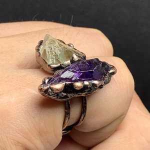 Close-up of vintage handmade ring featuring raw amethyst and green crystal stones