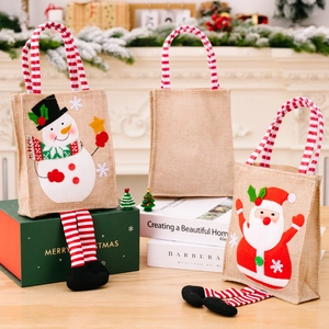 Three festive Christmas jute gift bags with striped legs and cartoon patterns in a cozy room