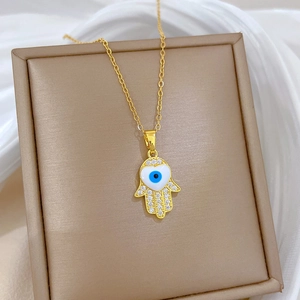 Detail of gold Hamsa hand pendant with evil eye and sparkling crystals on chain