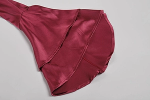 Dettaglio in raso bordeaux con eleganti volant a strati sui polsini del vestito da donna