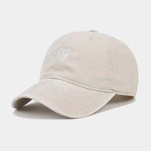 Détail de la broderie cœur sur une casquette en coton beige délavé de style vintage