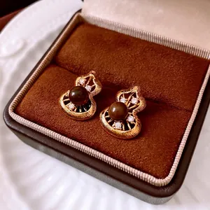 Gourd-shaped gold earrings with tiger eye stone and zircon in a velvet jewelry box