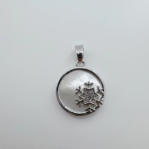 Macro view of a snowflake pendant featuring natural shell inlay and an 18K gold plated finish