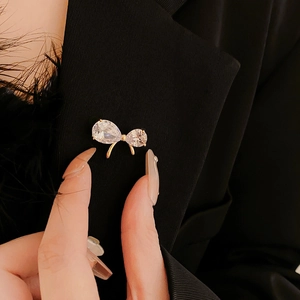 Close-up of a gold-plated bow brooch with pear-shaped zircons pinned to a black suit