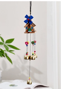 Detail of wooden windmill house wind chime with heart accents and four brass bells