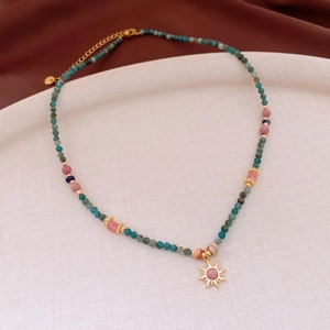 Detailed shot of retro sun pendant with natural turquoise beads and gold extension chain
