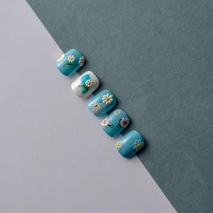 Détail de stickers à ongles marguerites 5D en relief sur faux ongles bleu clair