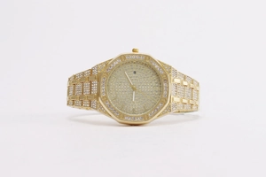 Detailed view of luxury gold-plated octagonal watch fully iced out with white crystals