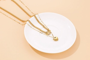 Detailed view of a gold double-layer necklace with heart pendant and T-bar clasp closure