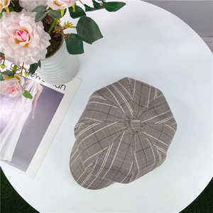 Top view of retro plaid newsboy cap with textured brown check pattern on a white table