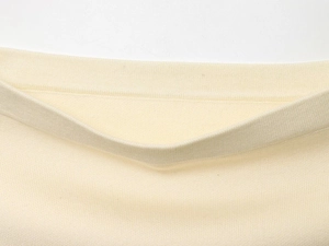 Detailed macro view of cream white knit fabric and ribbed hem texture for women's set