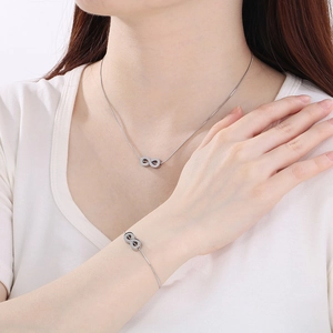 Polished silver infinity symbol necklace and bracelet set worn on model neck and wrist