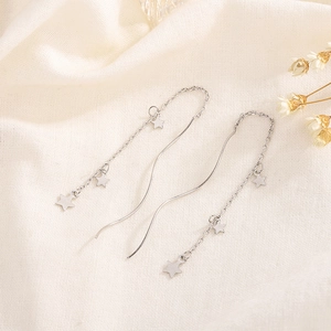 Elegant silver star threader earrings with dangling charms on textured fabric