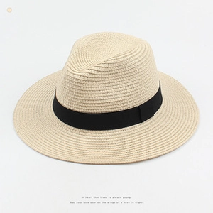 Close-up of beige straw sun hat featuring detailed weave texture and black ribbon bow
