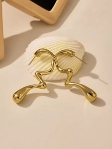 Détail macro de boucles d'oreilles vagues dorées sur un coquillage avec ombre artistique
