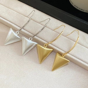 Macro view of gold and silver brushed metal triangle drop earrings on a velvet display