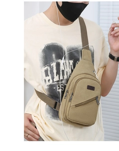 Khaki canvas chest bag with adjustable strap and dual front zipper pockets on model