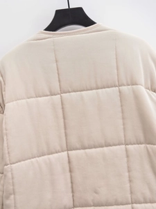 Detailed view of square quilting and twill texture on a beige casual jacket back