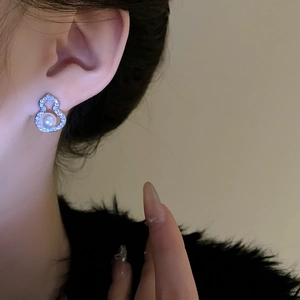 Detail of zircon gourd earring with pearl inlay shown on model with elegant pose