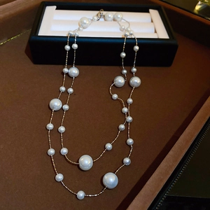 Detailed view of double-layered gold-plated necklace with elegant white pearls on velvet