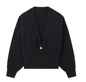 Detail of black knit cardigan featuring a V-neckline and a unique gold-tone button closure