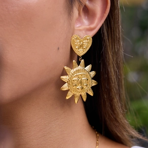 Boucles d'oreilles cœur et soleil en acier titane plaqué or 18k sur un mannequin